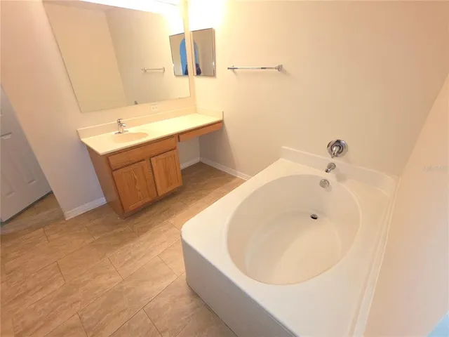 a bathroom with a tub sink and mirror