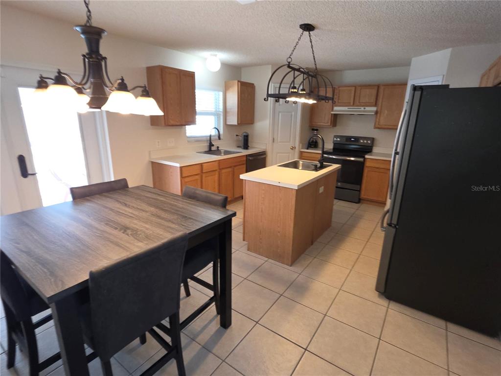 8388 Maltby Road Spring Hill, FL 34606 - Photo 5 of 28 a kitchen with stainless steel appliances kitchen island granite countertop a table chairs and a refrigerator