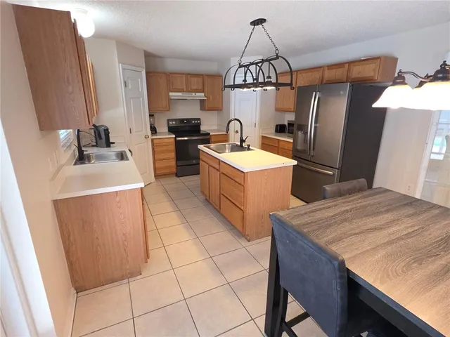 a kitchen with stainless steel appliances granite countertop a sink a stove a refrigerator a washer dryer and a dining table