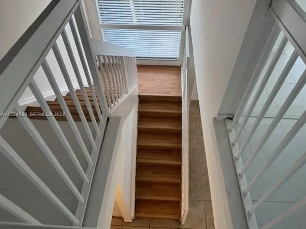 a view of staircase with white walls and railing