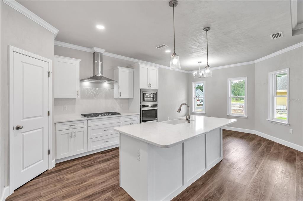1140 Southwest 67th Street Gainesville, FL 32607 - Photo 26 of 65 a large white kitchen with a stove a sink dishwasher and a refrigerator with wooden floor