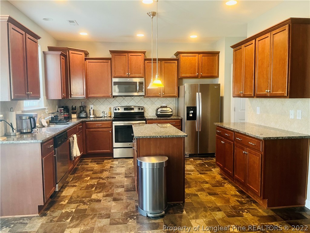 304 River Oak Street Spring Lake, NC 28390 - Photo 12 of 30 a kitchen with kitchen island granite countertop a sink counter top space a refrigerator and cabinets