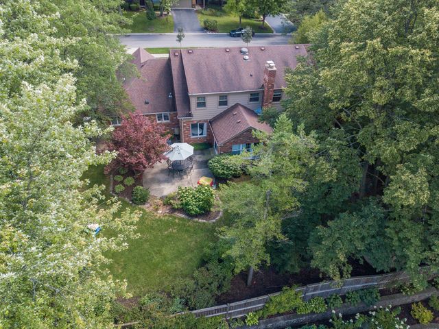 an aerial view of a house with a yard and tree s