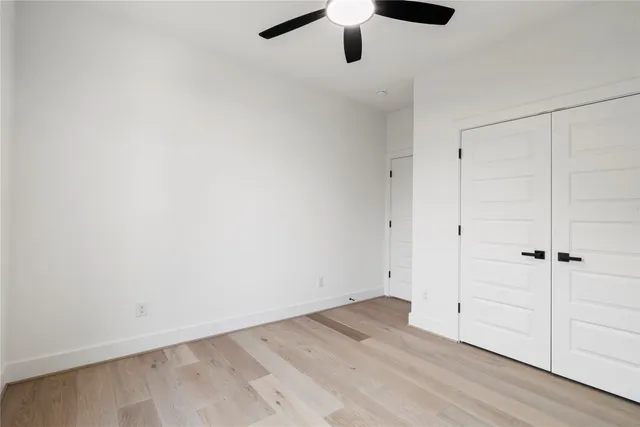 an empty room with a window and a ceiling fan