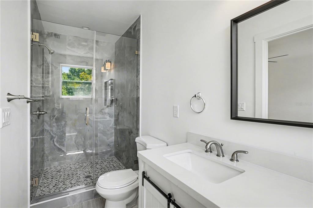 2328 West Spruce Street, Unit A Tampa, FL 33607 - Photo 13 of 15 a bathroom with a shower sink vanity mirror and toilet
