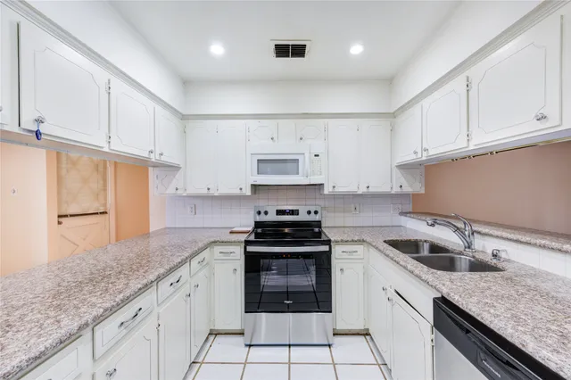 a kitchen with granite countertop a sink stove and cabinets