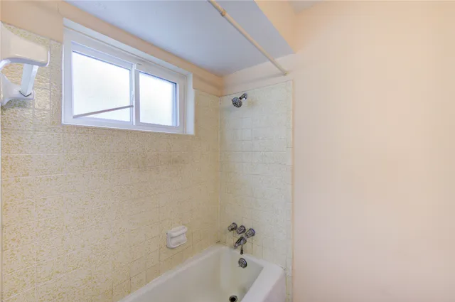 a bathroom with a bathtub a window and a shower