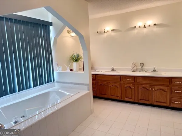 a bathroom with a tub a double vanity sink and a mirror