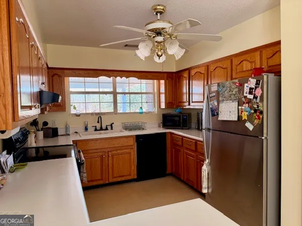 a kitchen with stainless steel appliances a sink a stove a refrigerator cabinets and a window