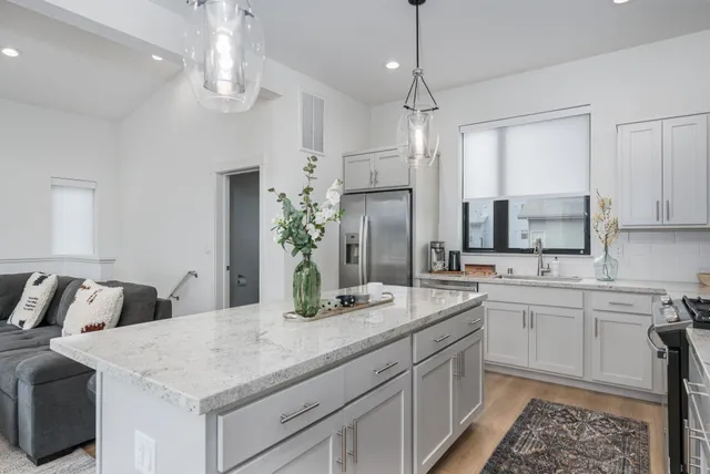a kitchen with kitchen island granite countertop a sink and refrigerator