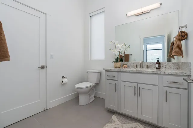 a bathroom with a granite countertop sink mirror and toilet