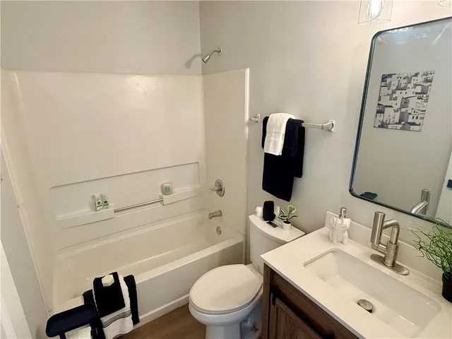 a bathroom with a toilet sink vanity tub and mirror