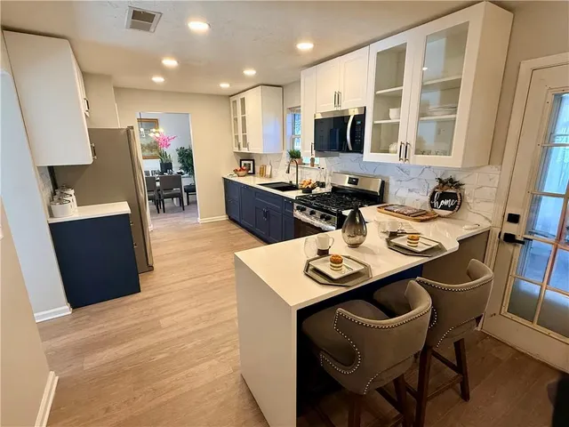 a kitchen with a sink a stove a kitchen island with chairs and wood floor