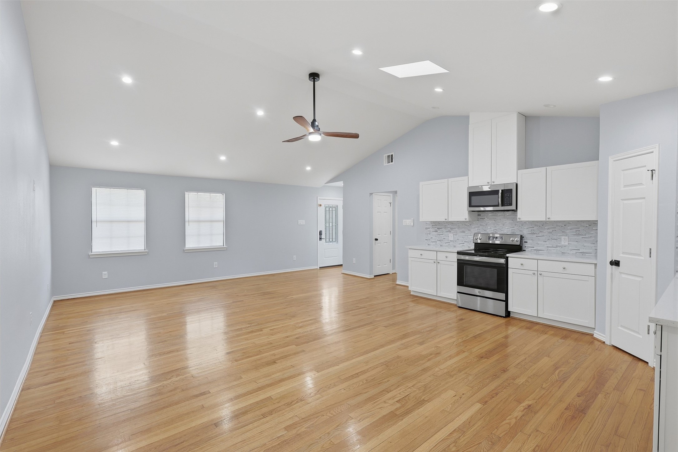 4926 Edfield Street Houston, TX 77033 - Photo 12 of 30 Spacious open-concept living area with vaulted ceilings, modern kitchen, and sleek hardwood floors, perfect for entertaining.