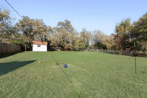 a view of a green field with tree in the background