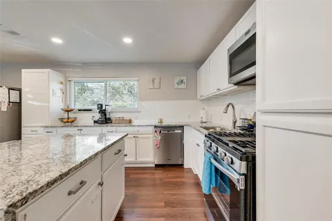 a kitchen with stainless steel appliances granite countertop a sink and a stove
