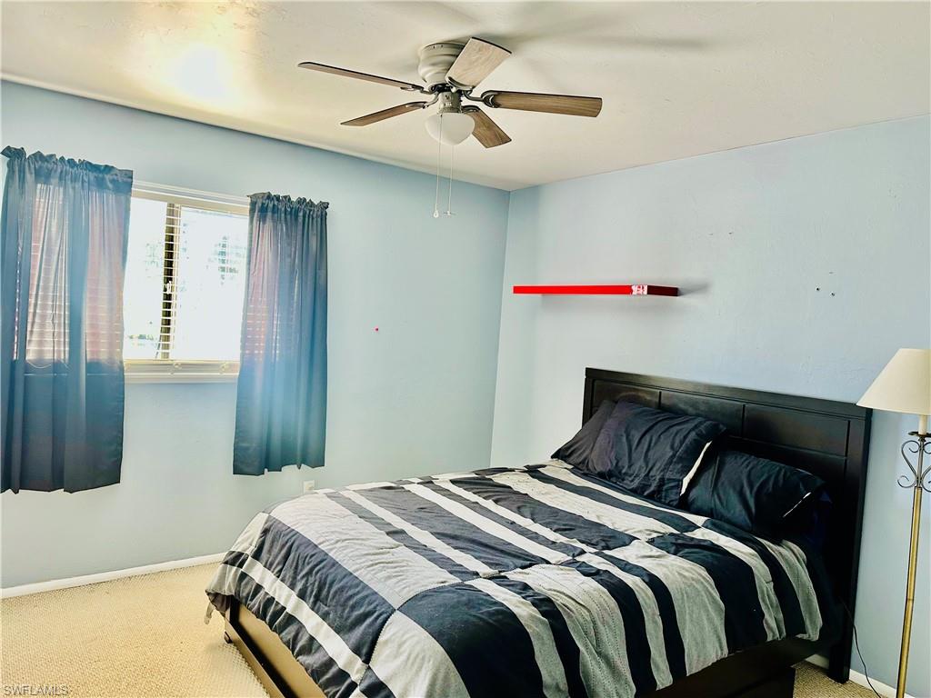 9108 Caloosa Road Fort Myers, FL 33967 - Photo 15 of 19 a bedroom with a bed and a chandelier
