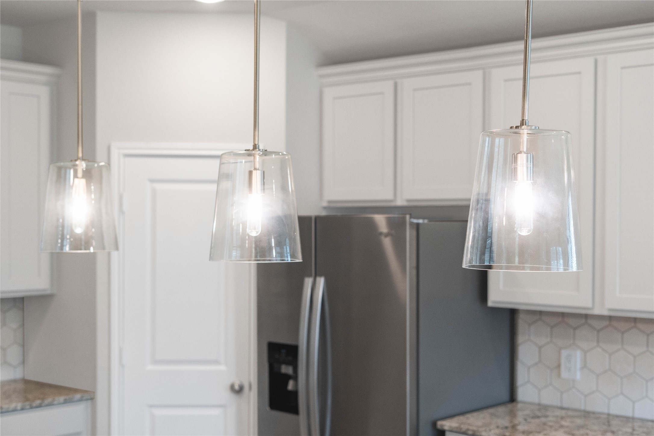 19645 Montgomery Rdg Way Montgomery, TX 77316 - Photo 17 of 41 Clarion Pendants Brushed Nickel pendant lights that hang over the kitchen island.