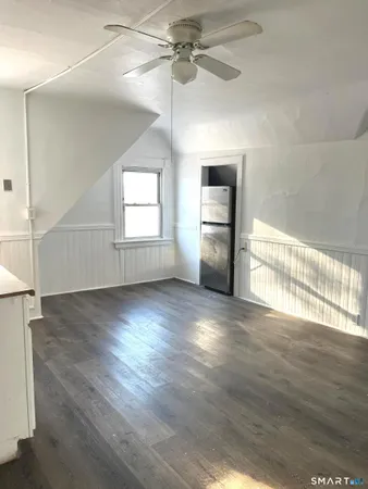 an empty room with wooden floor chandelier and windows