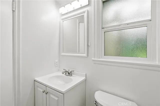 a bathroom with a toilet sink vanity and mirror