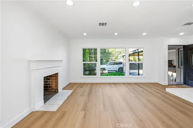 a view of an empty room with a fireplace and a window