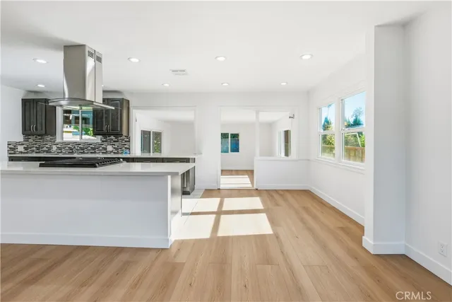 a view of a kitchen with kitchen island granite countertop wooden floor stainless steel appliances and a window