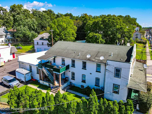 an aerial view of a house with swimming pool a yard and a large tree