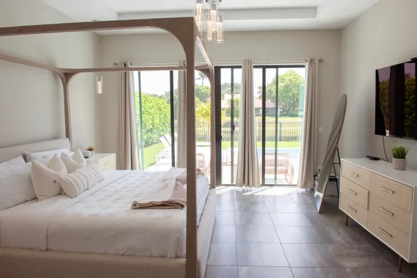 a large bedroom with a bed and a flat tv screen on dresser