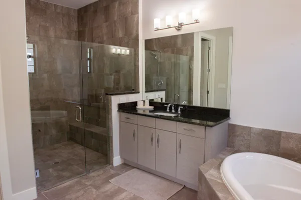 a bathroom with a granite countertop sink a toilet a mirror and shower