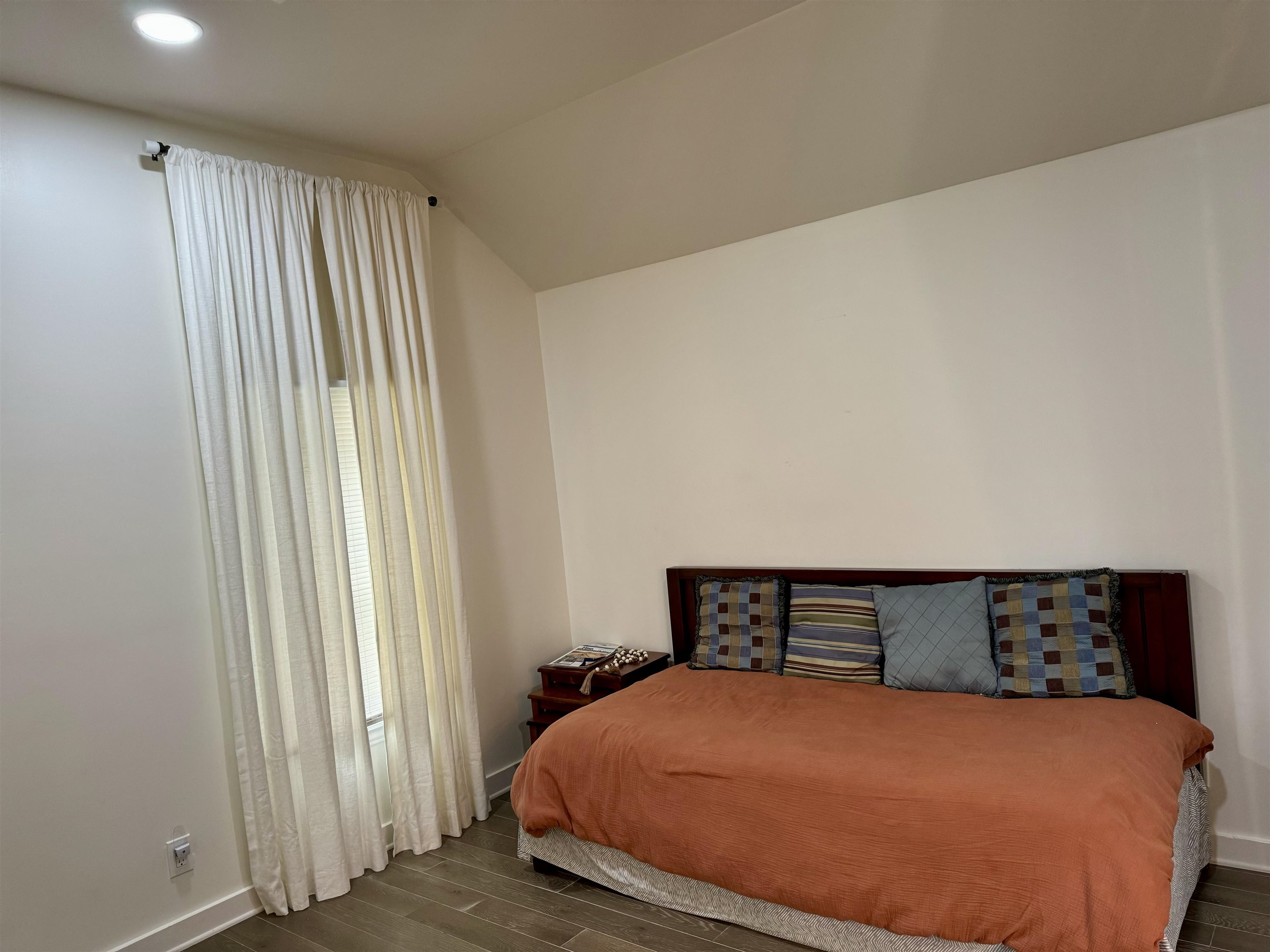 Bedroom featuring wood-type flooring, lofted ceiling, and multiple windows