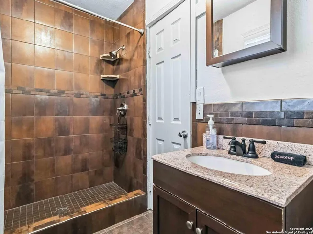 a bathroom with a granite countertop sink a mirror and shower