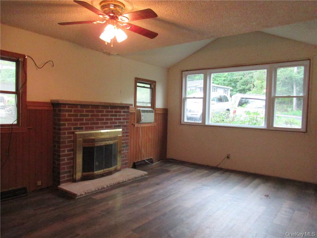 357 Mountain Lodge Road Monroe, NY 10950 - Photo 3 of 20 Unfurnished living room featuring dark hardwood / wood-style flooring, a fireplace, ceiling fan, and lofted ceiling
