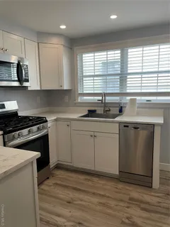 a kitchen with a sink stove cabinets and window