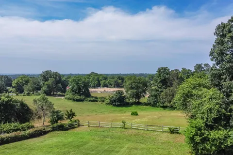 an aerial view of a residential houses with outdoor space and trees
