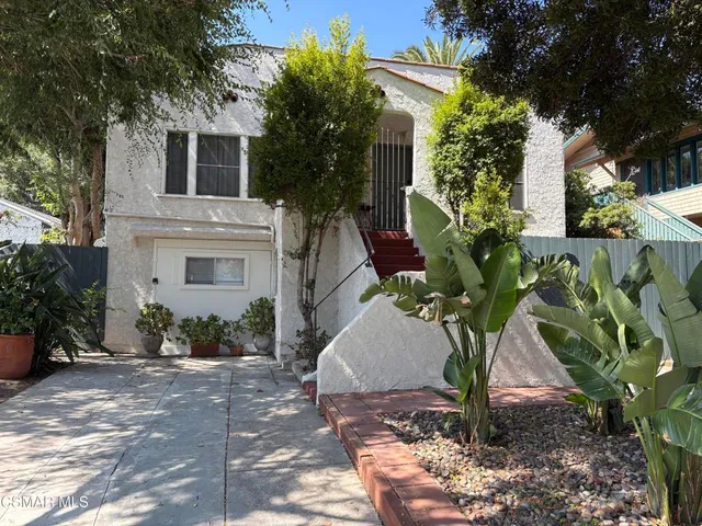 a vase of flowers sitting on a sidewalk