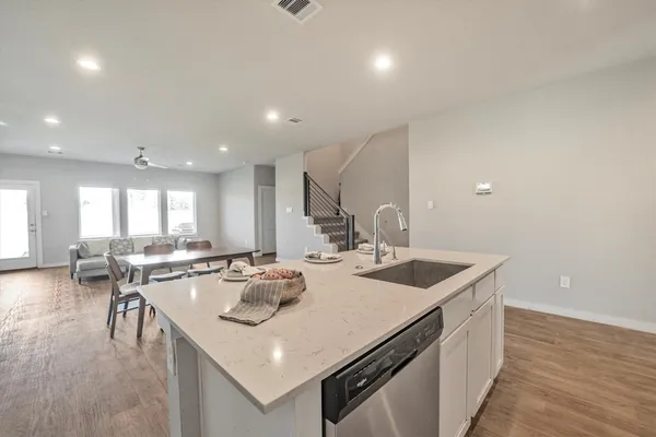 a kitchen with a sink a stove and chairs with wooden floor