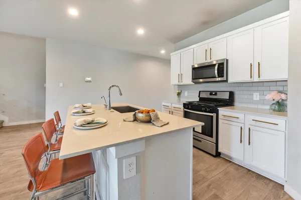 a kitchen with stainless steel appliances granite countertop a sink a stove a microwave a stove and white cabinets