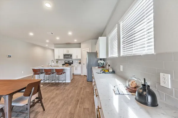 a kitchen with a sink a stove a kitchen island with chairs and wooden floor