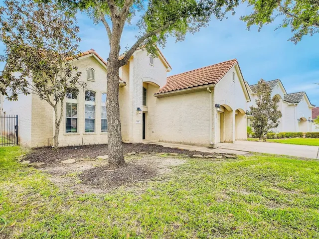 a view of yellow house with a large tree and wooden fence