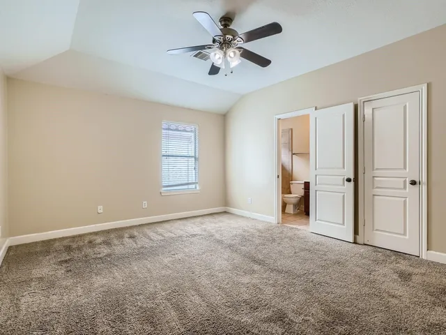 an empty room with closet and a ceiling fan
