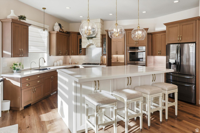 534 East Fish Hatchery Road Mantua, UT 84324 - Photo 19 of 87 Kitchen featuring a kitchen breakfast bar, two tone cabinets, stainless steel appliances, a kitchen island, and backsplash