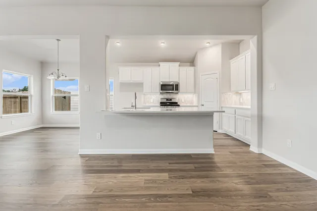 a kitchen with stainless steel appliances a refrigerator a stove top oven and wooden floors