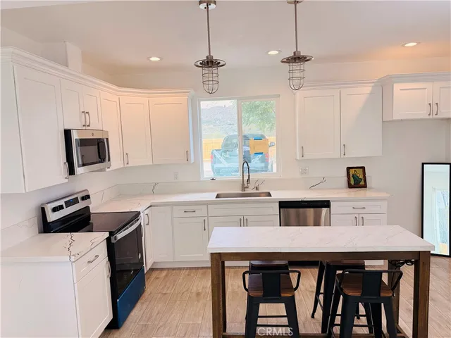 a kitchen with stainless steel appliances kitchen island granite countertop a table chairs sink and cabinets