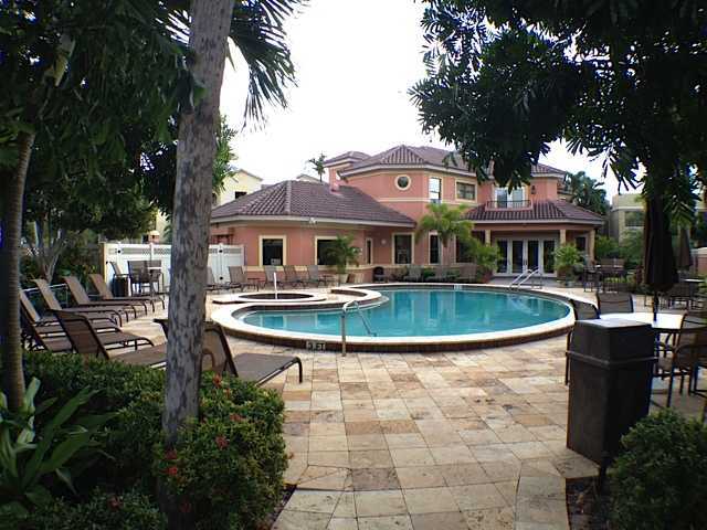 49 Uno Lago Drive Juno Beach, FL 33408 - Photo 16 of 18 a view of a white house with a swimming pool and a yard