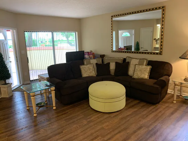 a living room with furniture and a large mirror next to a window