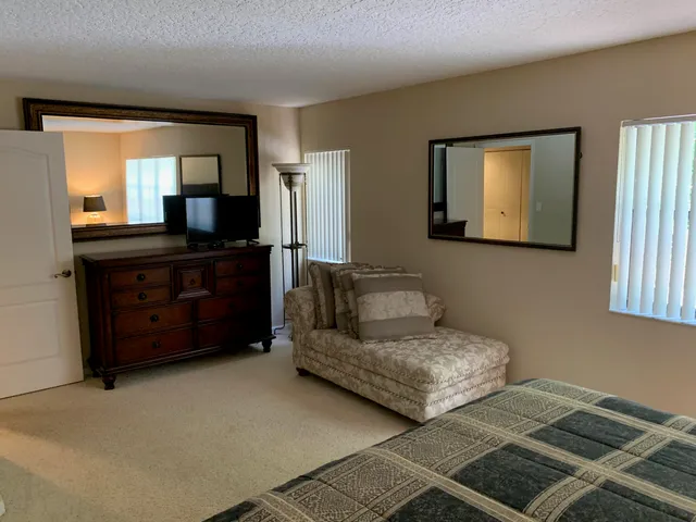 a living room with couches dresser and a large mirror next to a window
