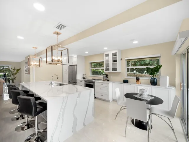a kitchen with stainless steel appliances kitchen island a table and chairs in it