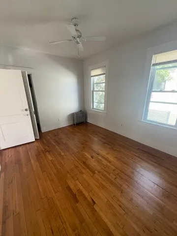 a view of empty room with window and wooden floor