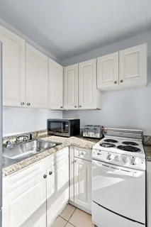 a kitchen with granite countertop white cabinets and white appliances