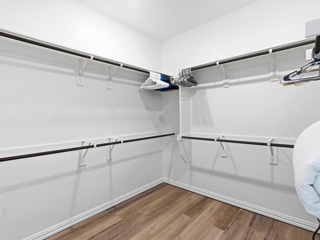 16936 Post Cedar Drive Justin, TX 76247 - Photo 14 of 30 Spacious walk-in closet featuring wood-finish flooring, white walls, and extensive built-in shelving with hanging rods
